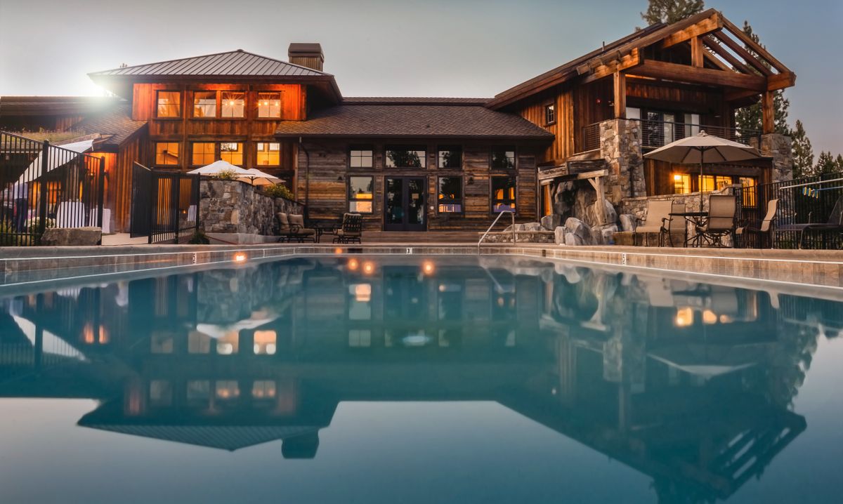 Piscine privée devant une maison en bois au crépuscule
